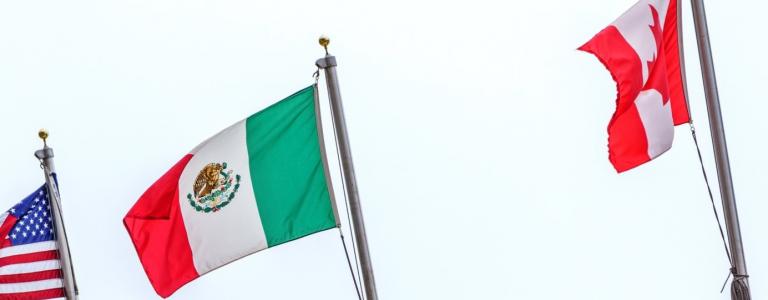 Flags of the United States, Mexico, and Canada hang side-by-side from a building