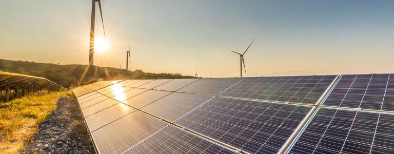 Image of windmills standing tall over solar panels