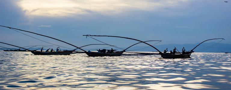 A fleet of traditional fishing boats in a lake at dusk