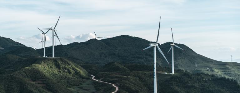 Wind turbines on rolling green hills and a blue sky