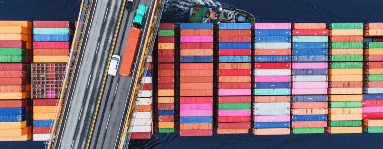 Container ship beneath a road with cars and lorries