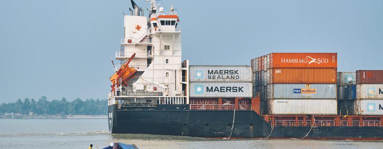 Small boat headed toward large container ship