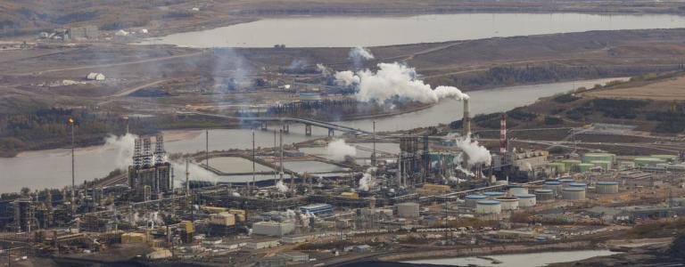 An aerial photo of an industrial plant with smoke billowing into the air from towers.