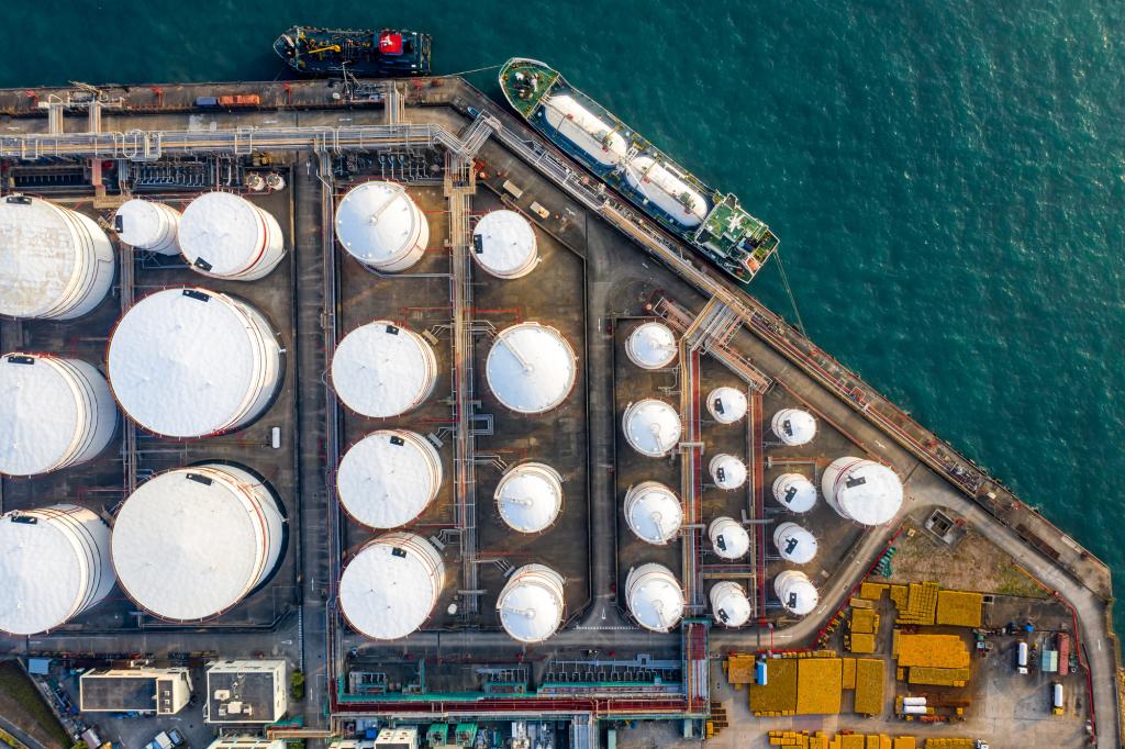 Oil refinery storage units with tanker ship viewed from above