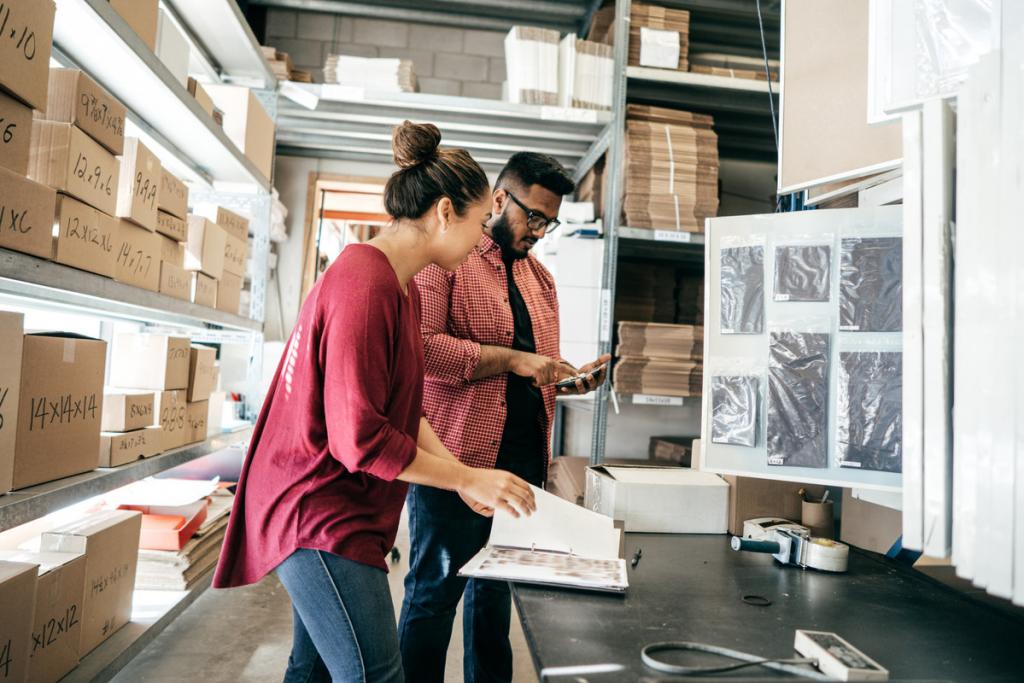 Young man and woman consult in a warehouse filled with cardboard boxes