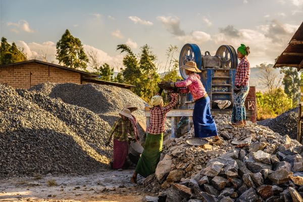 A group of women work at a small mine during the day surrounded by rocks